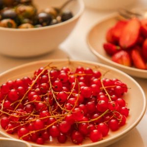 A vibrant display of fresh berries including red currants, strawberries, and grapes artfully arranged on a table.