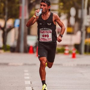 Athlete running in a marathon, staying hydrated. Outdoor city street scene.