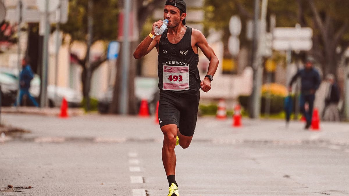 Athlete running in a marathon, staying hydrated. Outdoor city street scene.